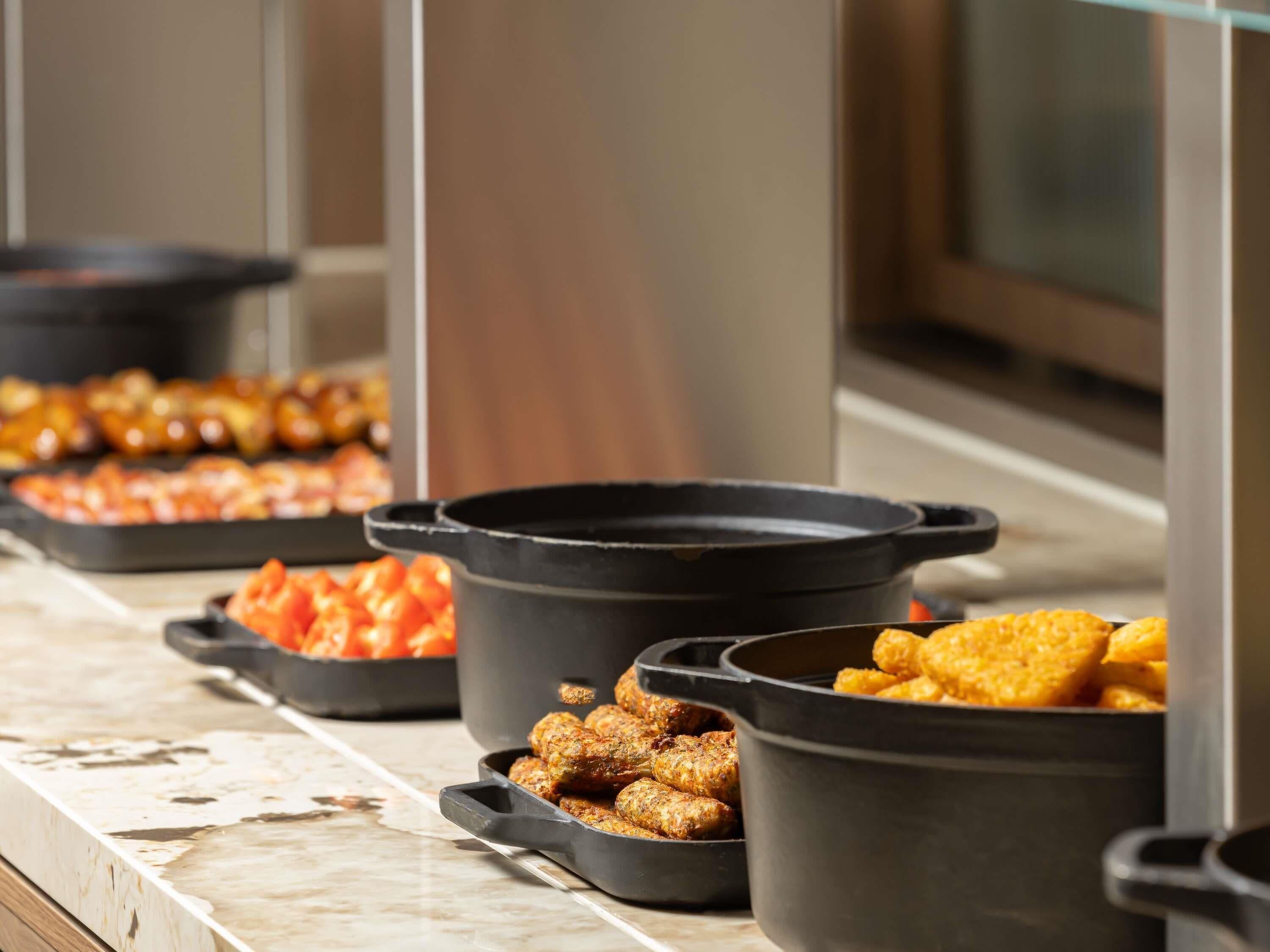 A buffet with various dishes in black serving containers.