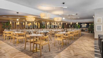 A restaurant with wooden furniture, pendant lighting, and a herringbone floor pattern.