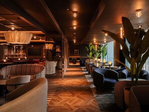 A modern lounge area with a herringbone wood floor, comfortable seating, and ambient lighting. - Mercure London Earls Court (London)