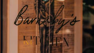 Een lijst met een bord waarop staat 'Barnaby's KITCHEN' en een deel van een plantje is te zien.