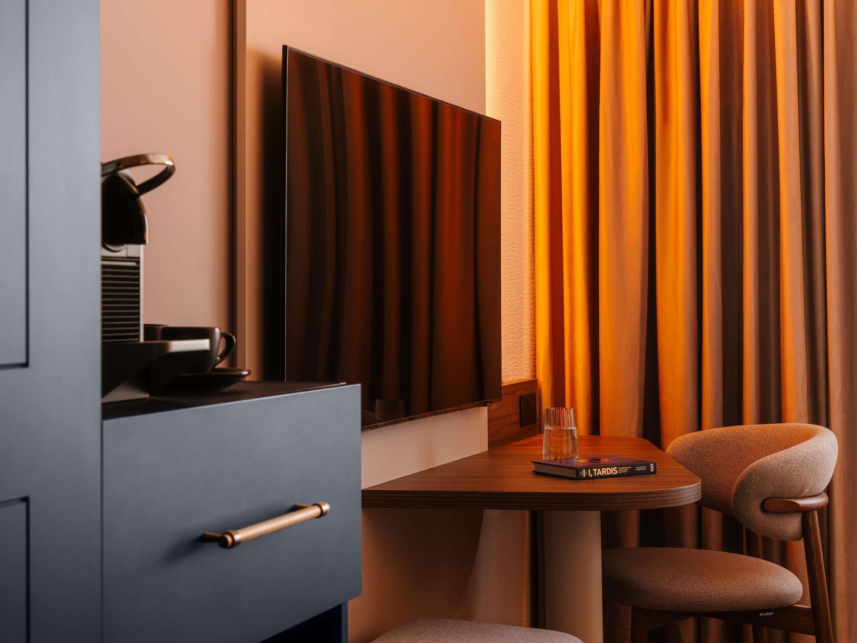 A modern hotel room with a desk, chair, and a large mirror.