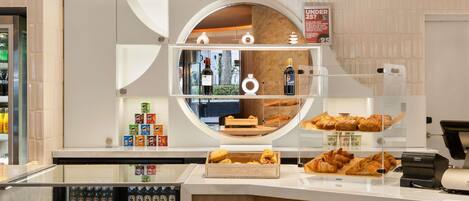 A bakery display with pastries, a refrigerator with beverages, and a sign indicating a discount for under 25.