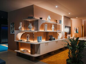 A modern interior with a central island, shelves with decorative items, and a potted plant. - Mercure London Earls Court (London)