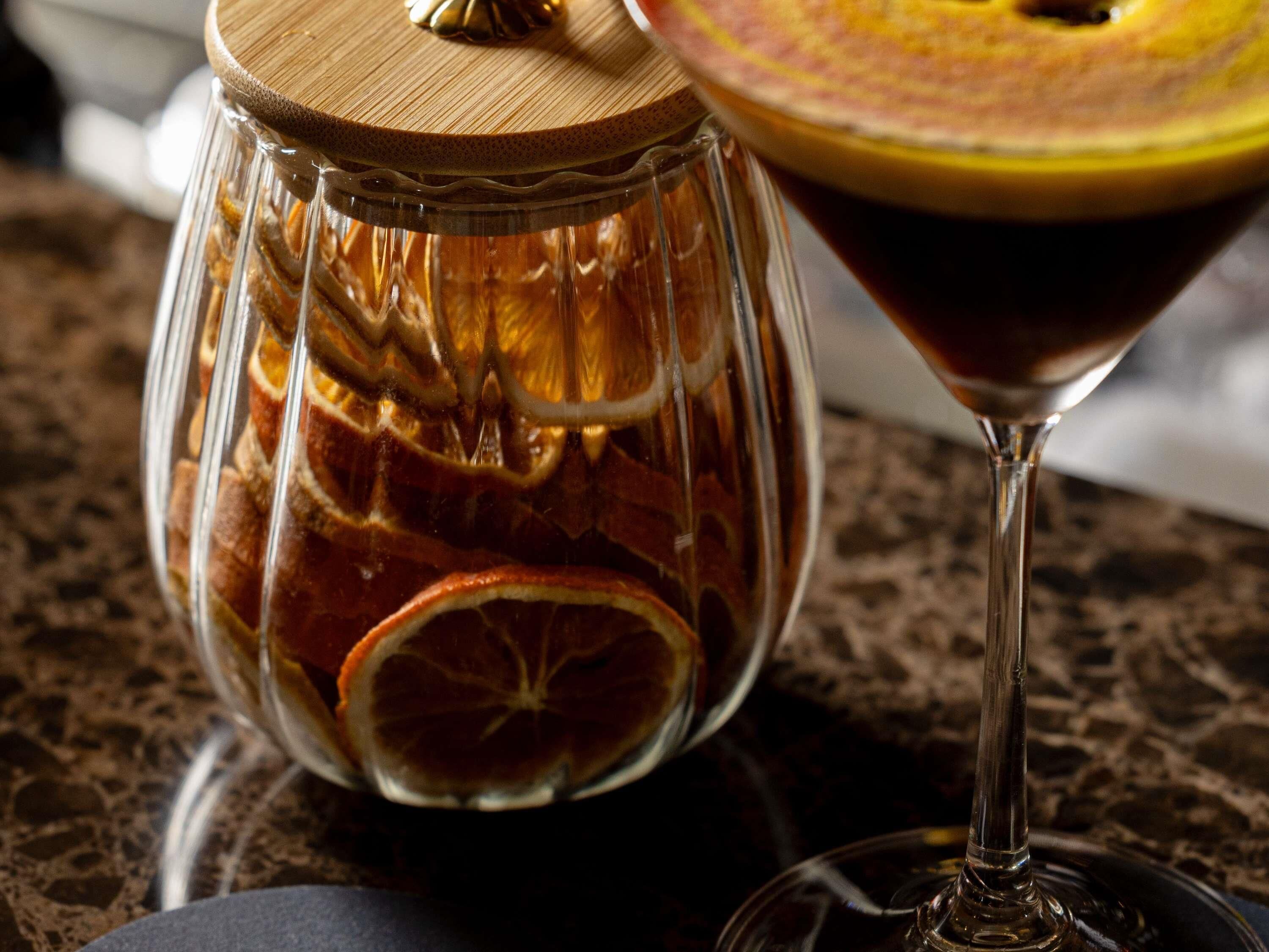 A glass container with dried orange slices and a martini glass with a lemon garnish.