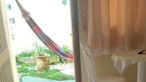 Een hotelkamer met een bed, een stoel, een tafel en uitzicht op de tuin.