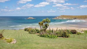 A coastal landscape with a grassy area, a small island, and a beach. - A large three bedroomed apartment in West Pentire, Crantock. (Crantock)