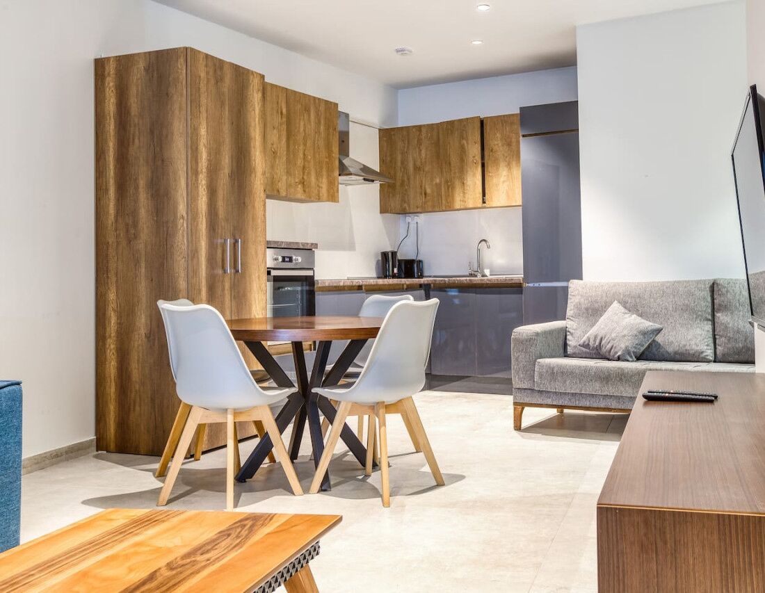 Una cocina moderna con armarios de madera, una mesa de comedor con sillas y un sofá gris.