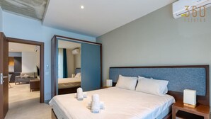 Una habitación de hotel moderna con una cama grande, una mesita de noche de madera y un área de descanso con sofá y una mesa.