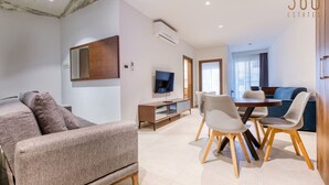 Una sala de estar moderna con sofá, mesa de comedor, sillas, televisor y aire acondicionado.