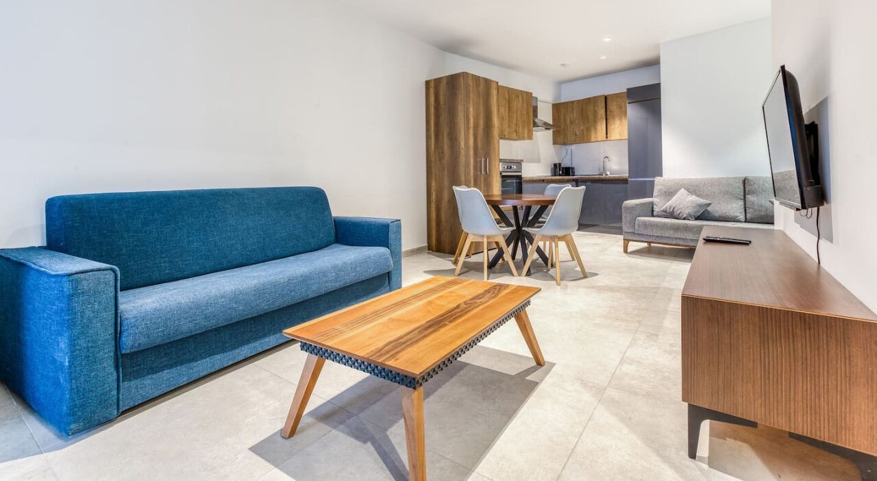 Un soggiorno moderno con un divano blu, un tavolino in legno e un'area pranzo con sedie.