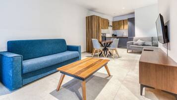 Un soggiorno moderno con un divano blu, un tavolino in legno e un'area pranzo con sedie.