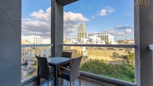 A balcony with a table and chairs, offering a view of surrounding buildings and a clear sky. - Designer, fully equipped 3BR home in Gzira w/WIFI (Il-Gżira)