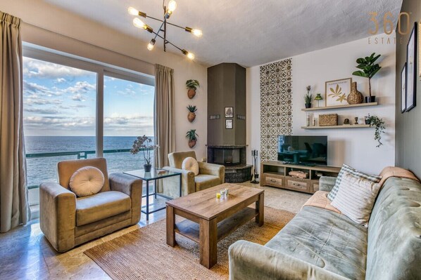 A modern living room with a large window, a fireplace, and a television. - Spacious seafront home with terrace, BBQ & Views ! (Tas-Sliema)