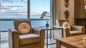 Habitació amb vista al mar, que disposa de dues butaques de pell, una taula de cafè de vidre i una petita planta en test.