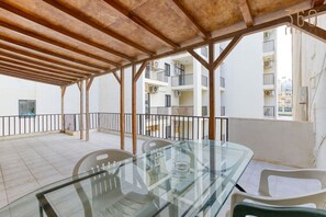 A covered outdoor area with a glass table and chairs, surrounded by a metal railing. - Spacious seafront home with terrace, BBQ & Views ! (Tas-Sliema)
