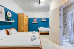 A hotel room with two beds, a wooden wardrobe, a shower area, and artwork on the walls. - Spacious seafront home with terrace, BBQ & Views ! (Tas-Sliema)
