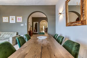 A dining area with a wooden table, green upholstered chairs, and framed artwork on the wall. - Spacious seafront home with terrace, BBQ & Views ! (Tas-Sliema)