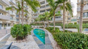 A modern apartment building with a swimming pool, palm trees, and a well-maintained garden. - Designer, luxurious 3BR home in Pender Gardens (San Ġiljan)