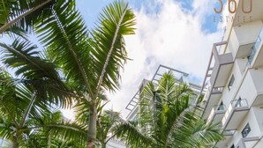 A modern multi-story residential building with balconies, surrounded by palm trees and a landscaped garden area. - Designer, luxurious 3BR home in Pender Gardens (San Ġiljan)