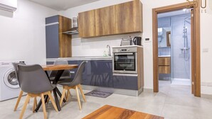 Eine moderne Küche mit Holdekor-Schränken, einem eingebauten Backofen und einer Essecke mit Tisch und Stühlen.