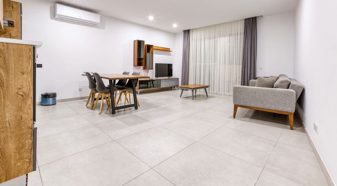 Una sala moderna con comedor, un sofá y un televisor.
