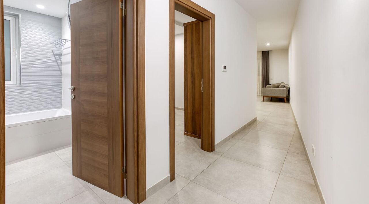 Un pasillo con puertas de madera, una bañera y un sofá al fondo.
