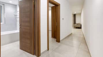 Un pasillo con puertas de madera, una bañera y un sofá al fondo.