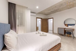 Un dormitorio moderno con cama, escritorio y espejo.
