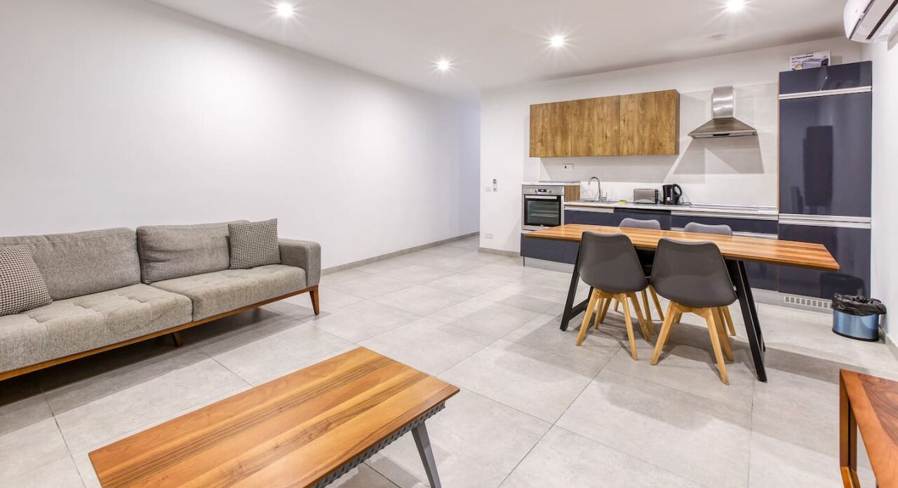Una sala moderna con sofá, una mesa de centro de madera y un comedor con sillas y una mesa.