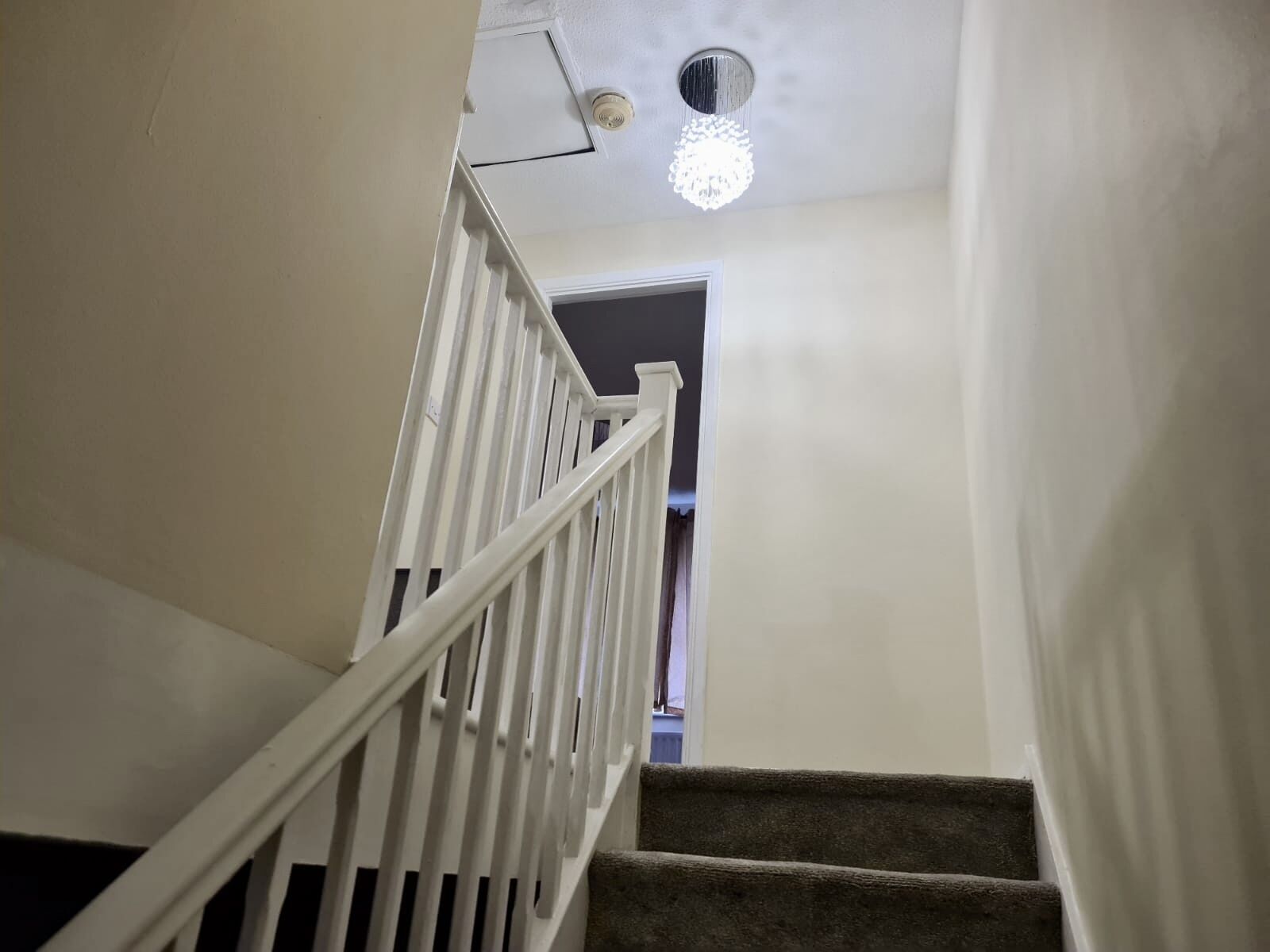 Una escalera con barandillas blancas que conduce a un rellano oscuro.