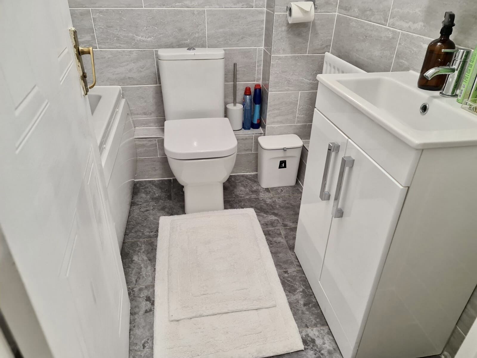A bathroom with a toilet, bidet, sink, and storage cabinets.