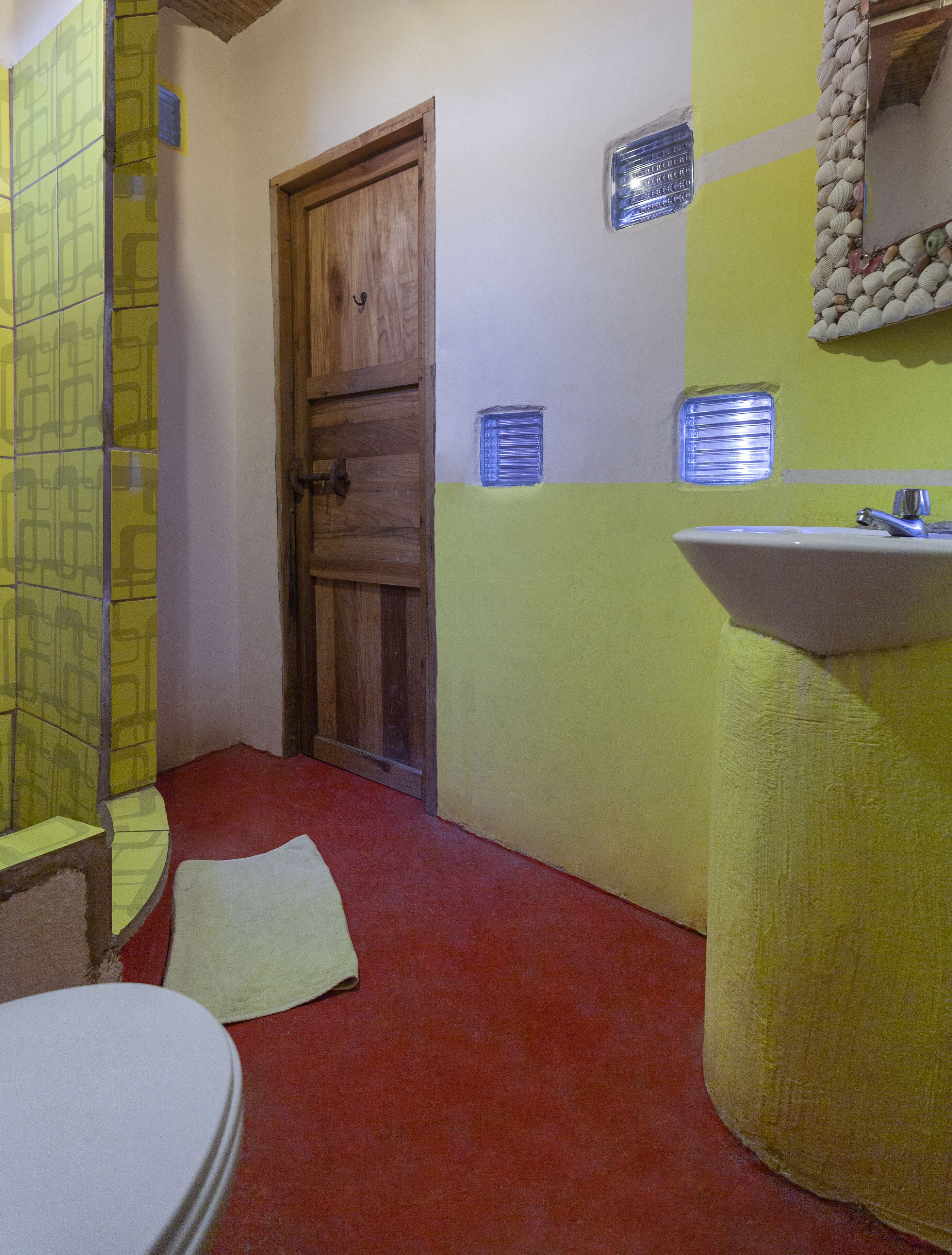 A bathroom with a wooden door, a sink, and a shower area.