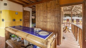 A room with a bamboo-framed table, a yellow wall, and a thatched roof outside. - La Casa Mompiche (Muisne)