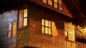 A two-story wooden house with multiple windows, a thatched roof, and a wooden balcony. - La Casa Mompiche (Muisne)