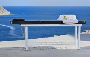 Relax on our outdoor terrace with a soothing ocean view, featuring a massage table and comfortable seating.