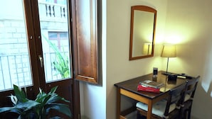 A hotel room with a wooden door, a small table with a lamp, a mirror, and a potted plant. - Cataneasy Rooms (Catania)