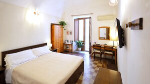 A bedroom with a bed, wooden wardrobe, desk, chair, and a potted plant. - Cataneasy Rooms (Catania)