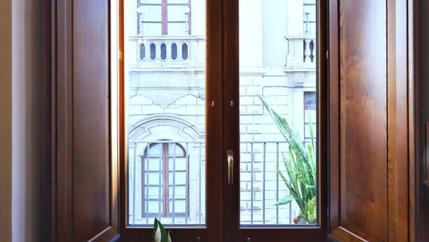A corner room with wooden doors and a view of a building with balconies. - Cataneasy Rooms (Catania)