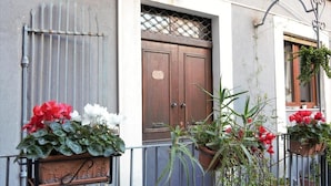A building with a wooden door, metal gate, and potted plants. - Cataneasy Rooms (Catania)