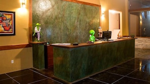 Een receptiebalie met een groene marmeren achtergrond, een ingelijst kunstwerk aan de muur en een computerscherm.