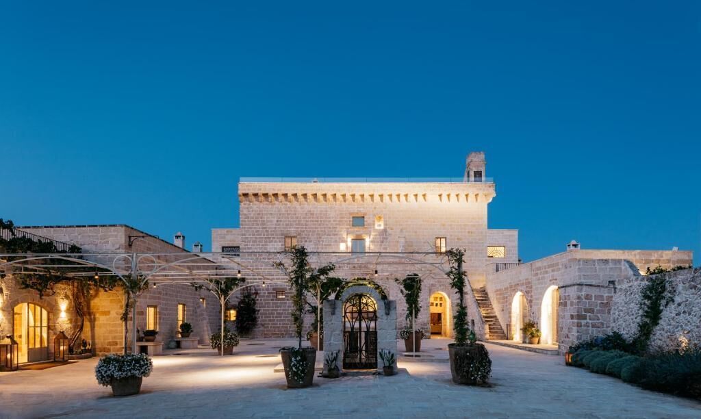 A historic stone building with a central courtyard, arched doorways, and a staircase leading to the upper levels.