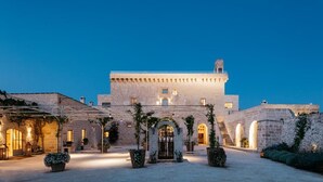 Un edificio histórico de piedra con un patio central, arcos y una escalera que lleva a los niveles superiores.