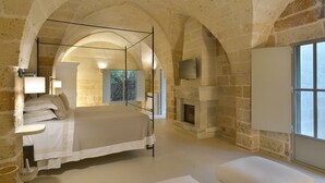 Un dormitorio con techo abovedado de piedra, una cama grande, chimenea y televisor montado en la pared.