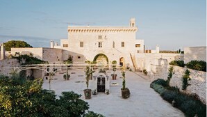 Un edificio histórico de piedra con un patio central, una entrada abovedada y una escalera que lleva a los niveles superiores.