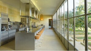 Una cocina moderna con una isla central, taburetes de bar y ventanas amplias que dan a un jardín.