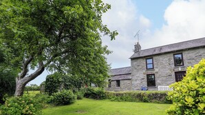 Une maison en pierre avec un grand arbre dans la cour.