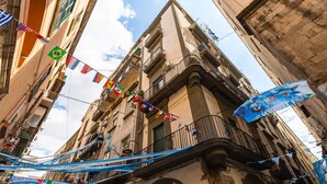A narrow street with buildings on either side, balconies, and flags. - Napoli Street Art Rooms - Wall by Wonderful Italy (Naples)