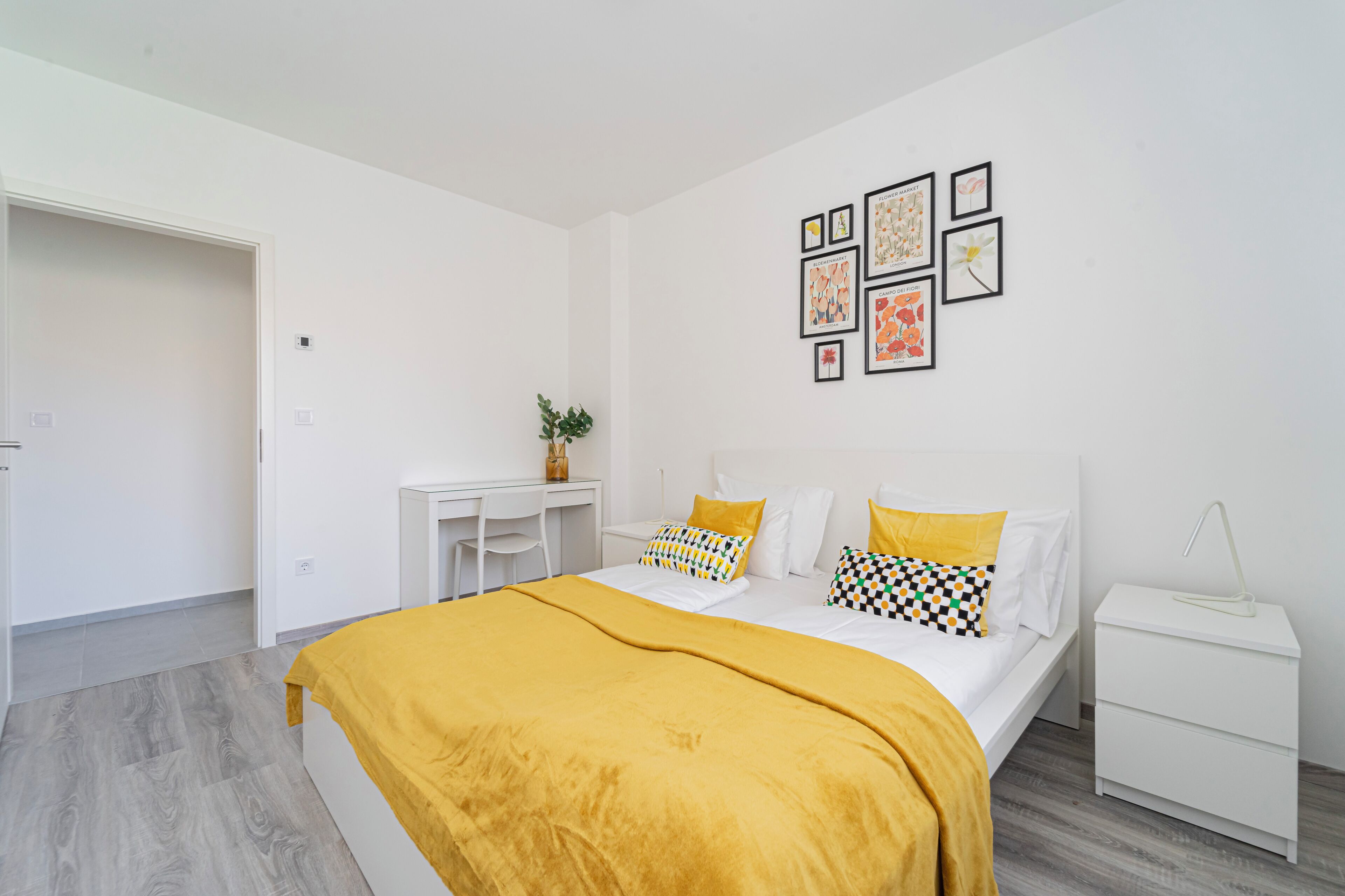 A bedroom with a bed, a desk, and a nightstand.