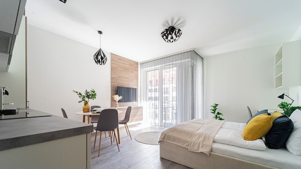 Una habitación moderna y bien iluminada con una cama, un escritorio y una zona de comedor.