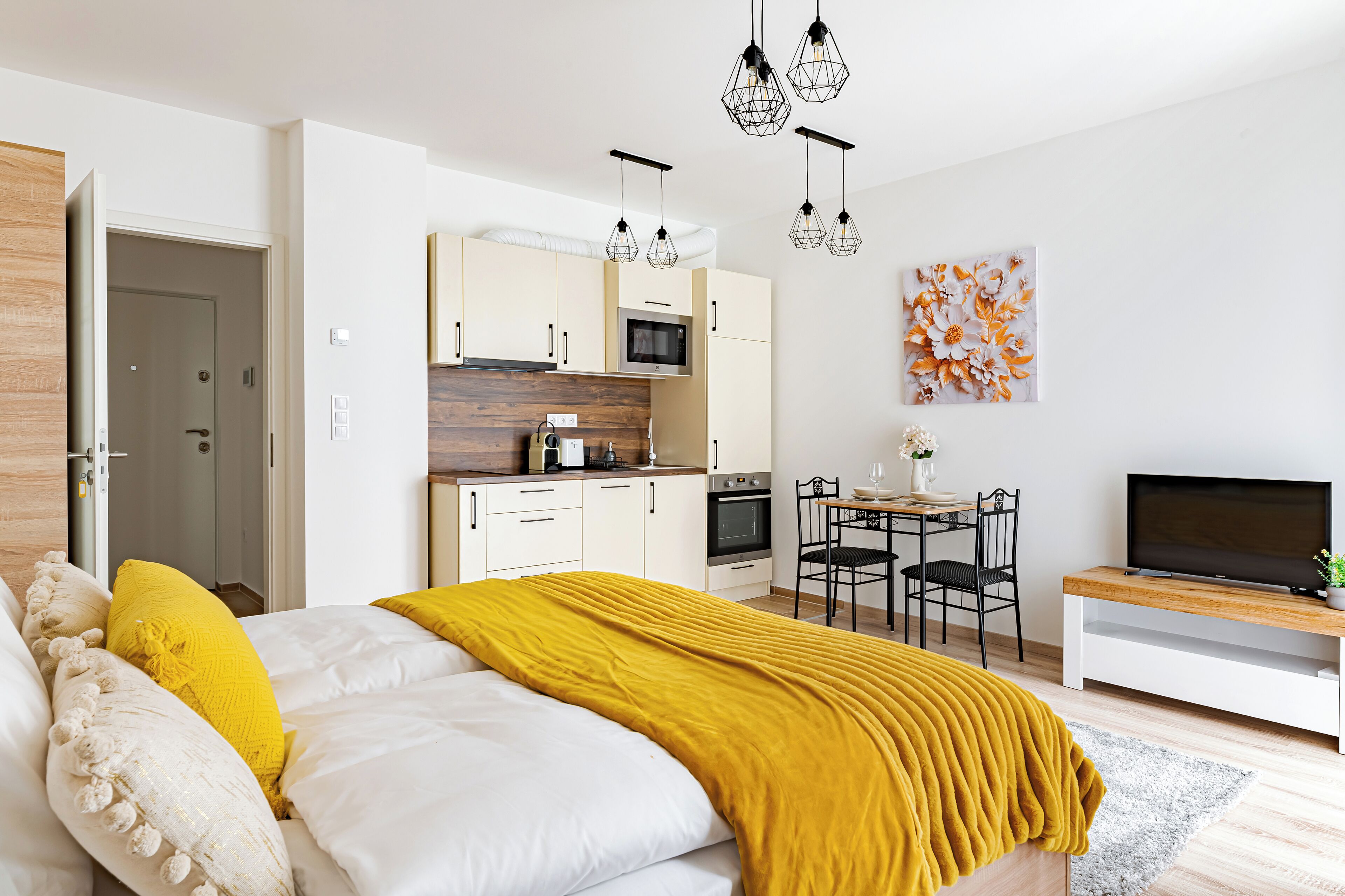 A modern bedroom with a bed, a dining area, and a kitchen.